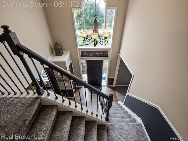 7235 Goldenrod Ct, Brighton, MI 48116 - stairway featuring a chandelier, a high ceiling, and carpet