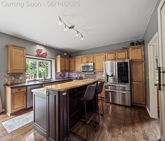 7235 Goldenrod Ct, Brighton, MI 48116 - kitchen with appliances with stainless steel finishes, a center island, dark wood finished floors, tasteful backsplash, and dark stone counters