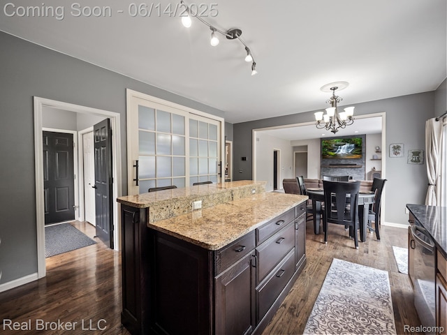 7235 Goldenrod Ct, Brighton, MI 48116 - kitchen featuring a chandelier, dark wood-style floors, light stone counters, a kitchen island, and decorative light fixtures