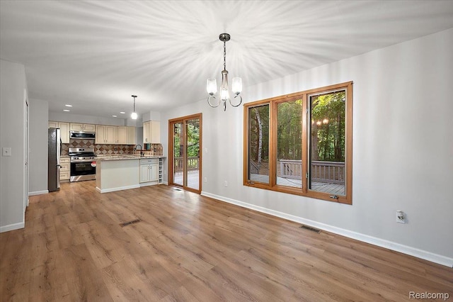 2696 Cedar Key Dr, Lake Orion, MI 48360 - kitchen featuring stainless steel appliances, open floor plan, backsplash, light wood finished floors, and a chandelier