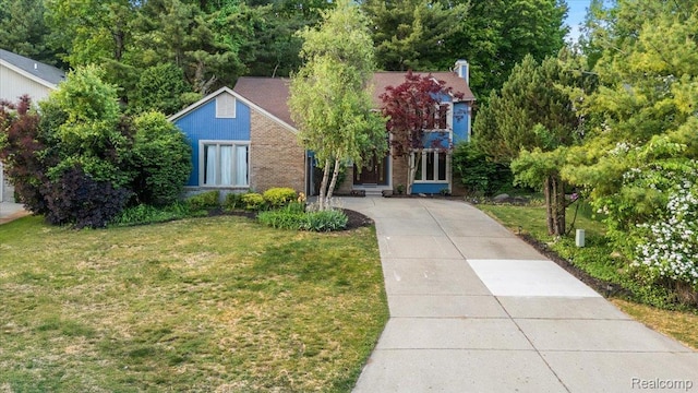 2696 Cedar Key Dr, Lake Orion, MI 48360 - view of property hidden behind natural elements featuring a front yard, driveway, brick siding, and a chimney