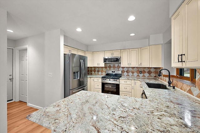 2696 Cedar Key Dr, Lake Orion, MI 48360 - kitchen with stainless steel appliances, cream cabinetry, backsplash, light wood finished floors, and light stone countertops