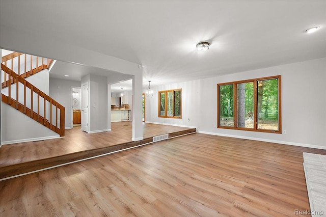 2696 Cedar Key Dr, Lake Orion, MI 48360 - unfurnished living room with wood finished floors, a chandelier, and stairway