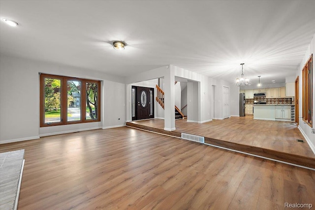 2696 Cedar Key Dr, Lake Orion, MI 48360 - unfurnished living room with a chandelier, light wood-type flooring, stairway, and beverage cooler