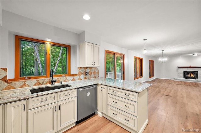 2696 Cedar Key Dr, Lake Orion, MI 48360 - kitchen with stainless steel dishwasher, a peninsula, decorative backsplash, light stone counters, and open floor plan