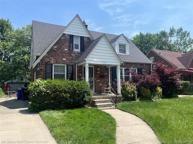 6334HERFORD Hereford St, Grosse Pointe, MI 48224 - view of front of home featuring brick siding, a front yard, a porch, a chimney, and a shingled roof