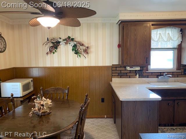 1811 Goddard Rd, Lincoln Park, MI 48146 - dining area featuring wainscoting, wallpapered walls, wood walls, and ceiling fan