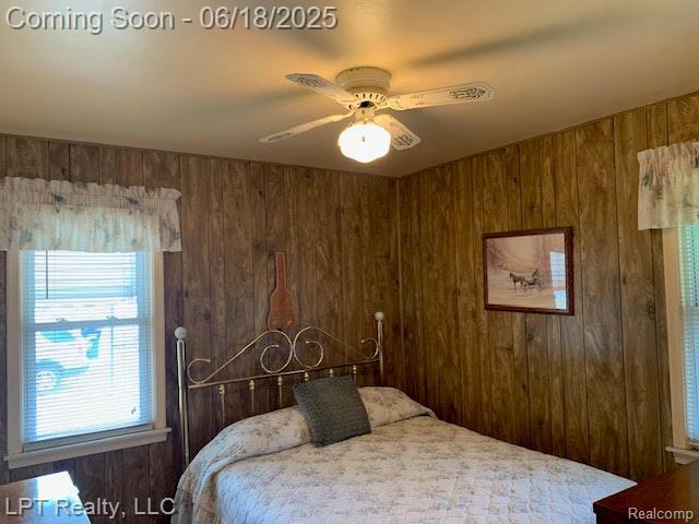 1811 Goddard Rd, Lincoln Park, MI 48146 - bedroom featuring wood walls, multiple windows, and a ceiling fan
