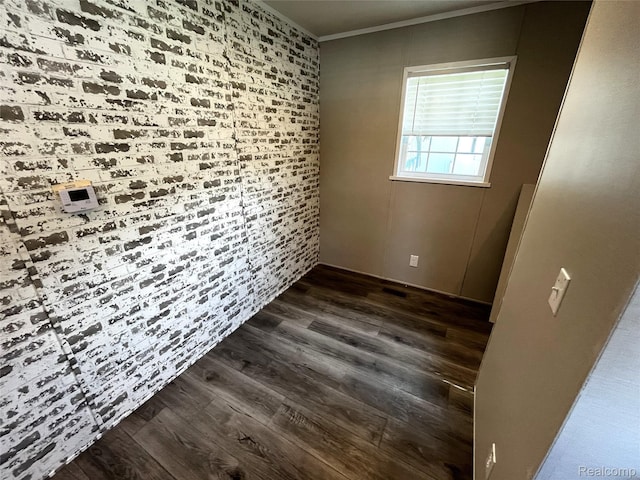 1048 Pheasant Dr, Bay City, MI 48706 - empty room featuring crown molding, dark wood finished floors, brick wall, and an accent wall