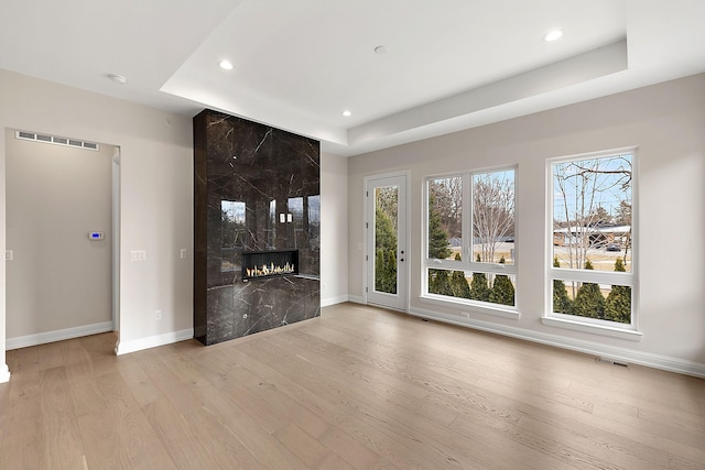 7479 Gramercy Cir W, Bloomfield, MI 48322 - unfurnished living room featuring recessed lighting, light wood finished floors, a premium fireplace, and a raised ceiling
