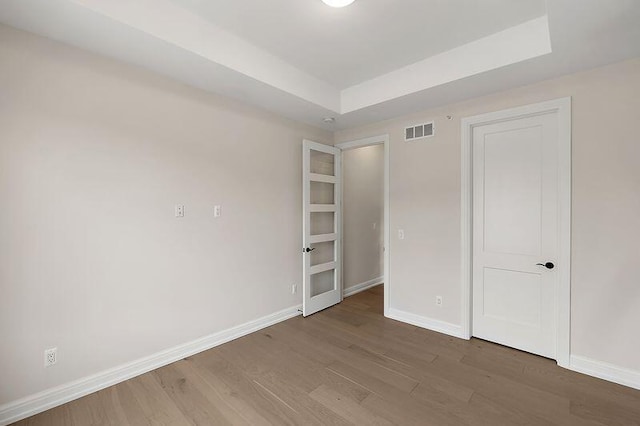 7479 Gramercy Cir W, Bloomfield, MI 48322 - unfurnished bedroom featuring a raised ceiling and wood finished floors