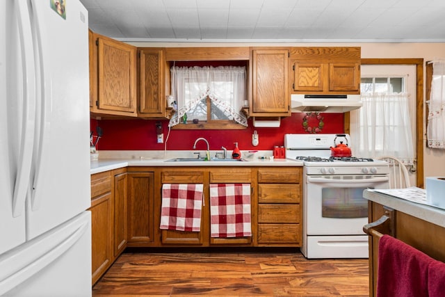 10765 Northland Dr, Big Rapids, MI 49307 - kitchen with white appliances, under cabinet range hood, light countertops, brown cabinets, and dark wood finished floors
