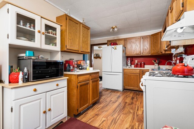 10765 Northland Dr, Big Rapids, MI 49307 - kitchen featuring white appliances, ventilation hood, light countertops, light wood-style flooring, and brown cabinets