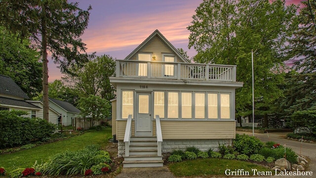 1194 Beach Dr, Holland, MI 49423 - view of front of home with a balcony, entry steps, and a yard