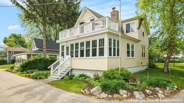 1194 Beach Dr, Holland, MI 49423 - view of side of property featuring a balcony, a chimney, and a yard