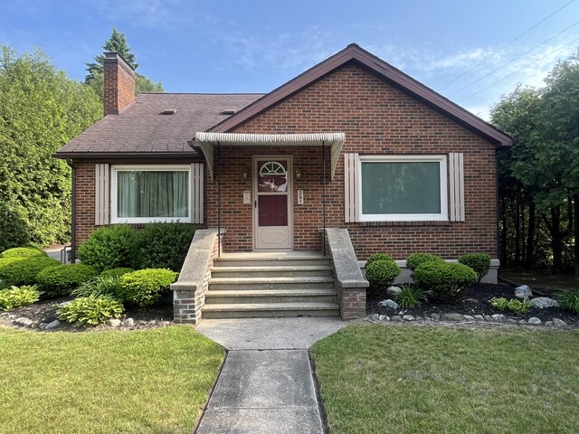 261 W Main St, Hart, MI 49420 - bungalow-style home with brick siding, a chimney, and a front lawn