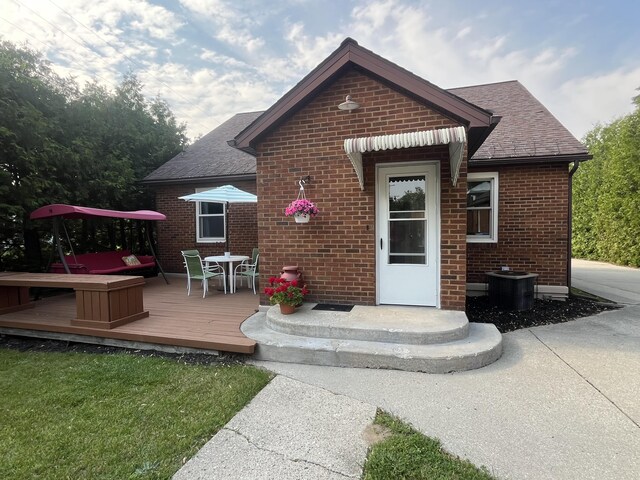 261 W Main St, Hart, MI 49420 - rear view of house with roof with shingles, brick siding, a wooden deck, and outdoor dining space