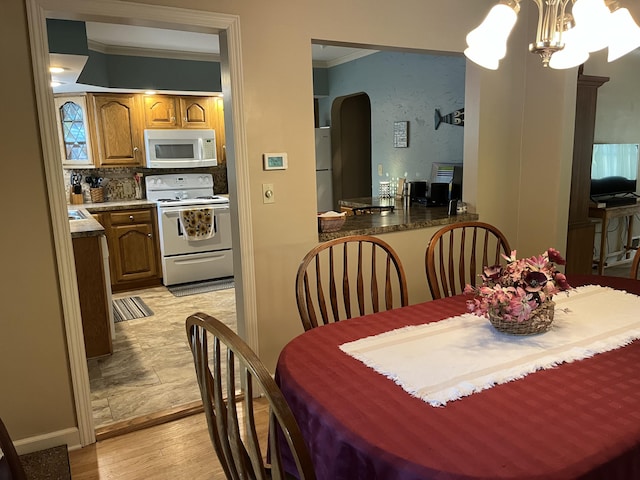 261 W Main St, Hart, MI 49420 - dining room with arched walkways, crown molding, a chandelier, and light wood finished floors