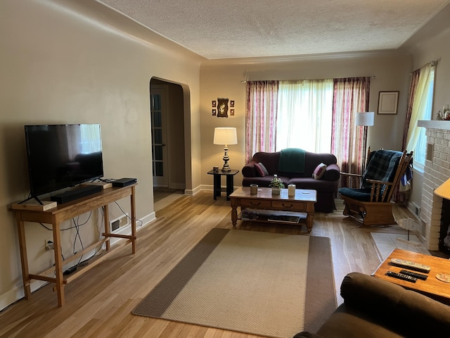 261 W Main St, Hart, MI 49420 - living room with arched walkways, a textured ceiling, wood finished floors, and a brick fireplace