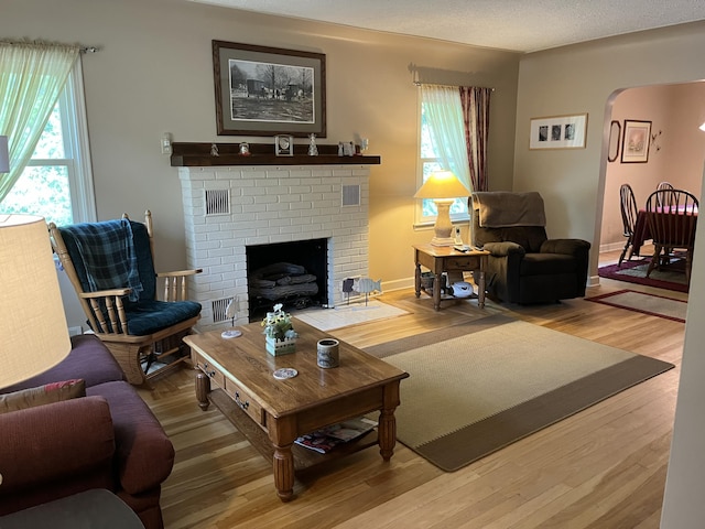 261 W Main St, Hart, MI 49420 - living area featuring arched walkways, plenty of natural light, light wood-style flooring, and a brick fireplace