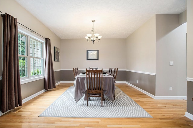 17872 Victors Ln, Marshall, MI 49068 - dining room featuring a chandelier, light wood-style floors, and a textured ceiling