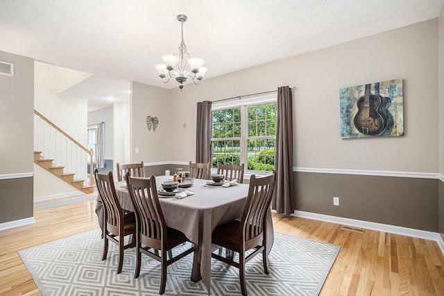 17872 Victors Ln, Marshall, MI 49068 - dining area featuring a chandelier, light wood-style flooring, stairway, and a textured ceiling