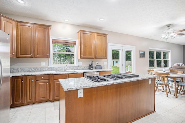 17872 Victors Ln, Marshall, MI 49068 - kitchen with appliances with stainless steel finishes, light stone counters, a ceiling fan, a center island, and light tile patterned flooring