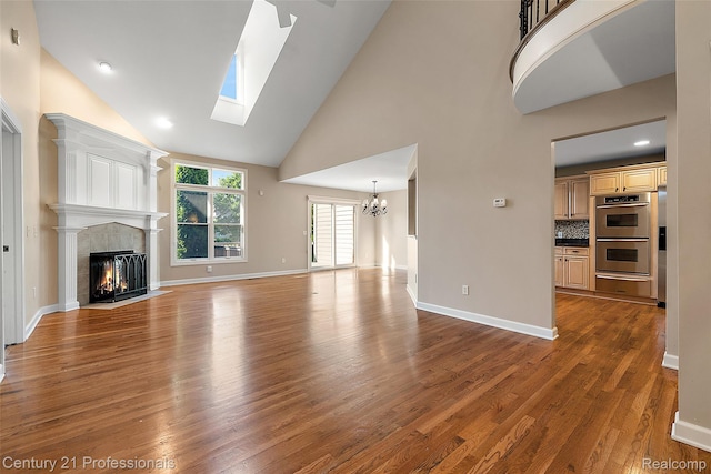 4013 Ardsley Ct, Clarkston, MI 48348 - unfurnished living room with high vaulted ceiling, a chandelier, wood finished floors, a tile fireplace, and a skylight