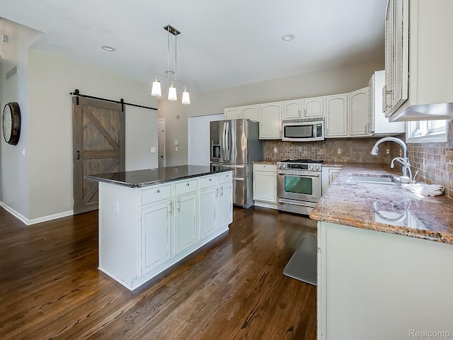 8595 Eastway Dr, White Lake, MI 48386 - kitchen featuring appliances with stainless steel finishes, white cabinets, dark wood finished floors, a barn door, and a center island