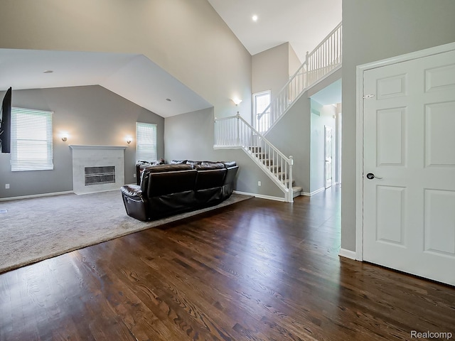 8595 Eastway Dr, White Lake, MI 48386 - living room featuring wood finished floors, stairs, a glass covered fireplace, and high vaulted ceiling
