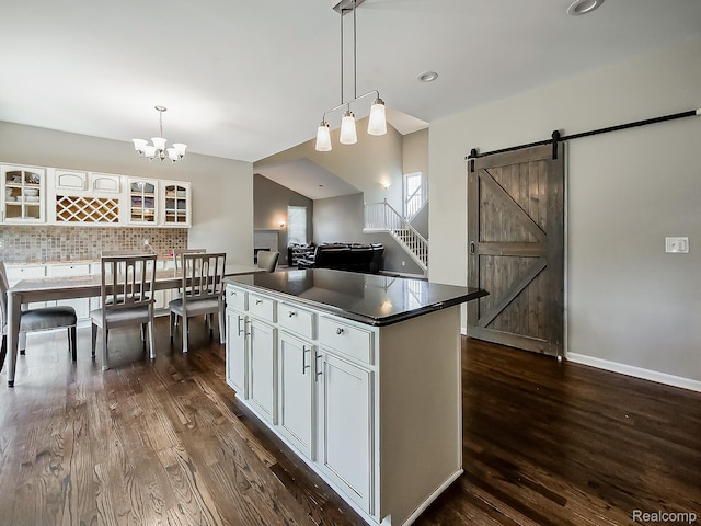 8595 Eastway Dr, White Lake, MI 48386 - kitchen with dark countertops, dark wood finished floors, a kitchen island, white cabinetry, and tasteful backsplash