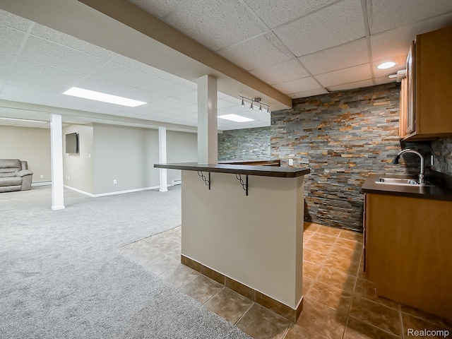 8595 Eastway Dr, White Lake, MI 48386 - kitchen with a drop ceiling, dark countertops, brown cabinets, a kitchen breakfast bar, and tile patterned flooring