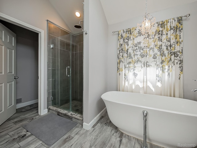 8595 Eastway Dr, White Lake, MI 48386 - bathroom featuring a shower stall, a freestanding bath, vaulted ceiling, wood finished floors, and a chandelier