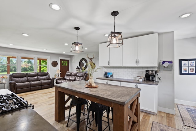 13936 Allen Rd, Clinton, MI 49236 - kitchen featuring dark countertops, white cabinetry, light wood finished floors, decorative backsplash, and recessed lighting