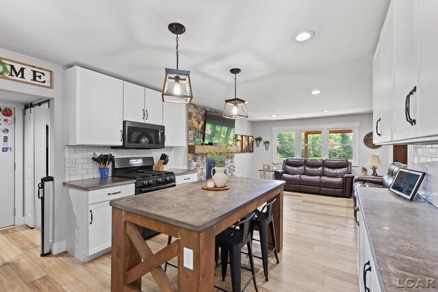 13936 Allen Rd, Clinton, MI 49236 - kitchen featuring gas range, a stone fireplace, backsplash, white cabinetry, and recessed lighting