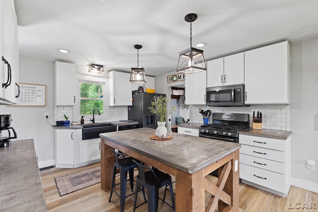 13936 Allen Rd, Clinton, MI 49236 - kitchen with stainless steel microwave, black fridge with ice dispenser, range with gas cooktop, white cabinets, and recessed lighting