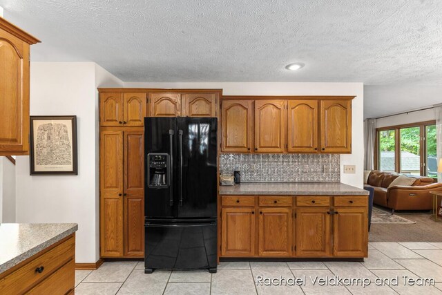 1579 Geddes Ave NW, Grand Rapids, MI 49534 - kitchen with black fridge, brown cabinets, light tile patterned flooring, a textured ceiling, and tasteful backsplash