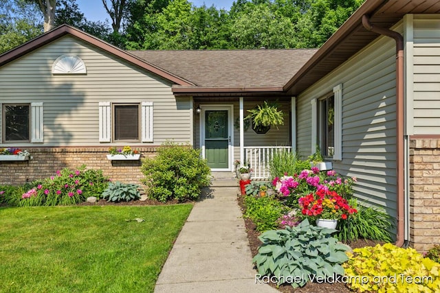 1579 Geddes Ave NW, Grand Rapids, MI 49534 - doorway to property with brick siding, covered porch, a lawn, and a shingled roof