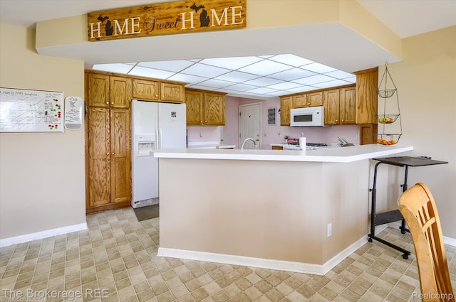 1484 E Baldwin Rd, Grand Blanc, MI 48439 - kitchen with white appliances, brown cabinetry, a peninsula, and light countertops