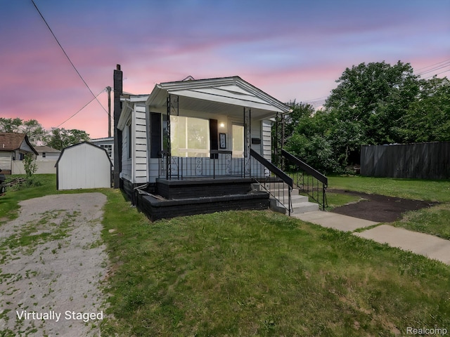 1309 Wood St, Monroe, MI 48161 - view of front facade with a chimney, a porch, a storage unit, and driveway