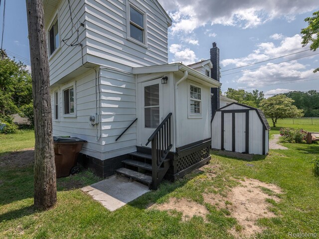 1309 Wood St, Monroe, MI 48161 - view of home's exterior with entry steps, a shed, a chimney, and a lawn