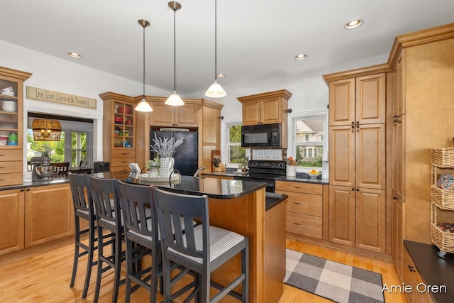 307 N Jefferson St SE, Lowell, MI 49331 - kitchen featuring black appliances, dark countertops, light wood finished floors, a kitchen island, and a breakfast bar area