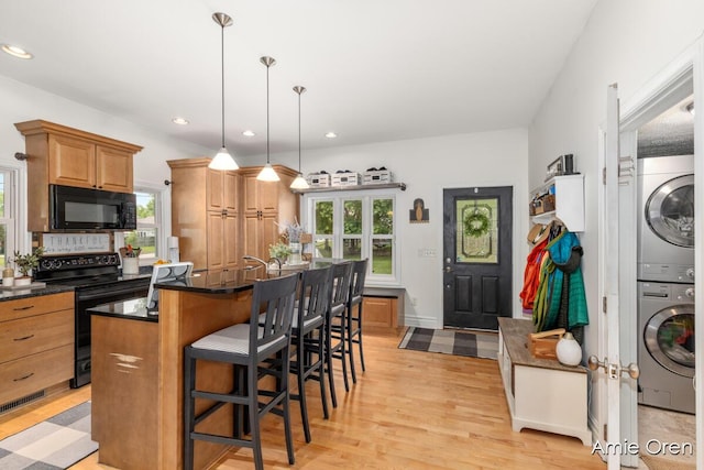 307 N Jefferson St SE, Lowell, MI 49331 - kitchen featuring black appliances, stacked washing machine and dryer, dark countertops, plenty of natural light, and recessed lighting