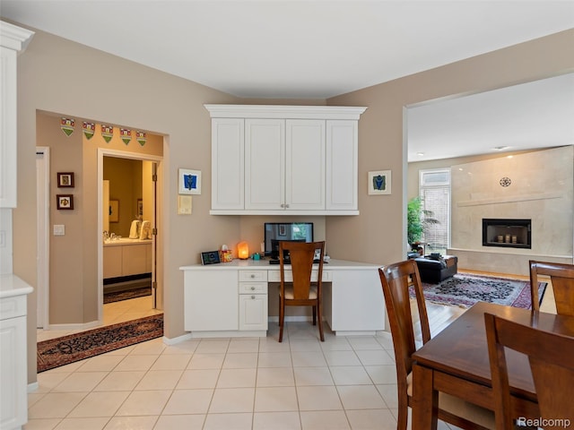 7304 Colchester Ln, West Bloomfield, MI 48322 - kitchen with built in desk, light countertops, white cabinetry, and a tile fireplace