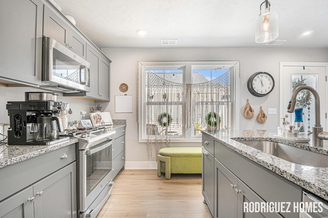 6678 S Square Ln, Rockford, MI 49341 - kitchen with appliances with stainless steel finishes, gray cabinets, light wood-type flooring, light stone counters, and recessed lighting