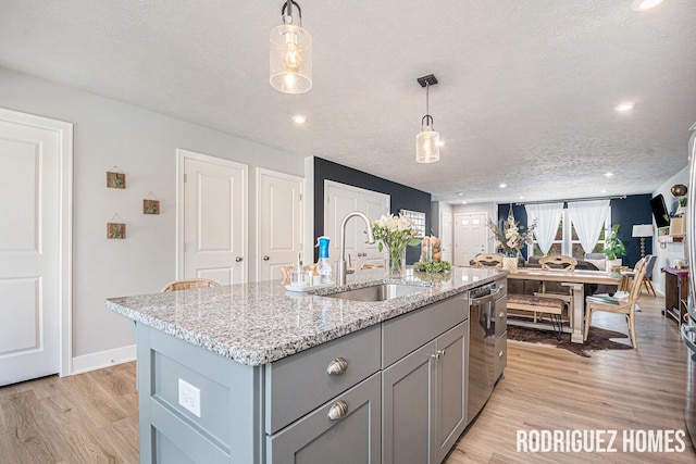 6678 S Square Ln, Rockford, MI 49341 - kitchen with gray cabinetry, light wood finished floors, dishwasher, an island with sink, and light stone counters