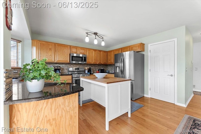 26957 Blue Heron Dr, Flat Rock, MI 48134 - kitchen with appliances with stainless steel finishes, decorative backsplash, light wood-style flooring, butcher block countertops, and a center island