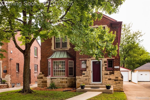 3924 Yorkshire Rd, Detroit, MI 48224 - tudor house featuring an outdoor structure, stone siding, a standing seam roof, a garage, and brick siding