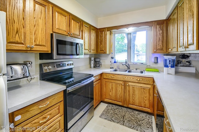 1038 Cora Dr, Flint, MI 48532 - kitchen featuring appliances with stainless steel finishes, brown cabinetry, and light countertops