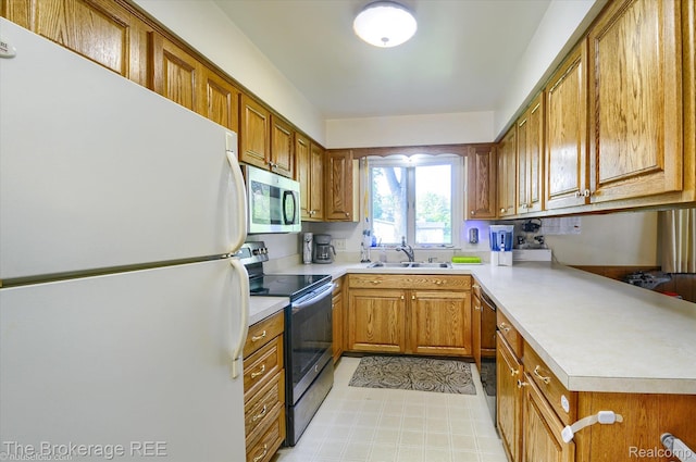 1038 Cora Dr, Flint, MI 48532 - kitchen with appliances with stainless steel finishes, brown cabinetry, light countertops, and a peninsula